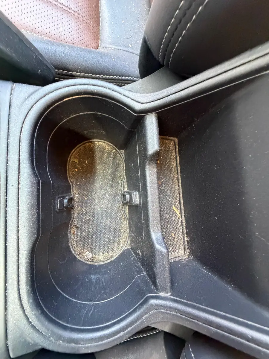 Subaru Innenraum vor der Aufbereitung, verschmutzter Getränkehalter in der Mittelarmlehne – KFZ-Aufbereitung Siebers