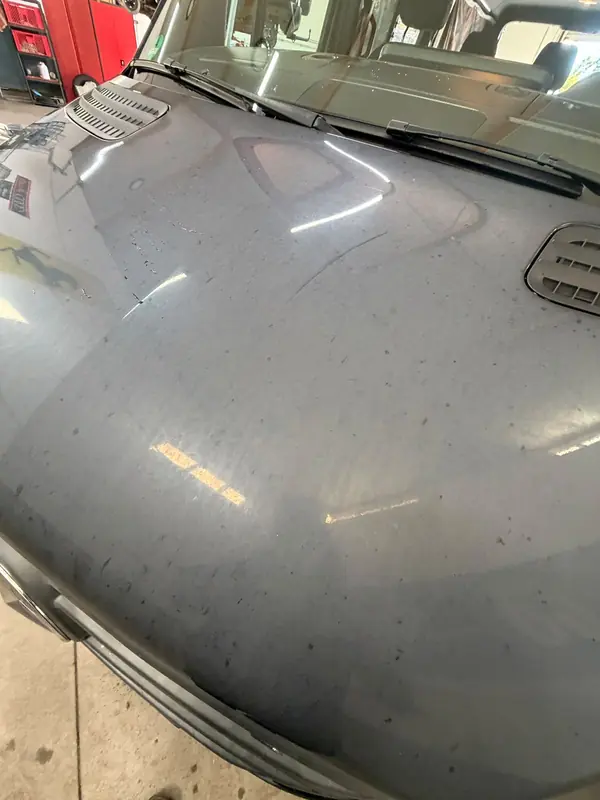 Motorhaube des Mercedes Sprinter vor der Politur, matte Fläche mit Kratzern und Wasserflecken im Streiflicht – Siebers KFZ-Reinigung und Pflege