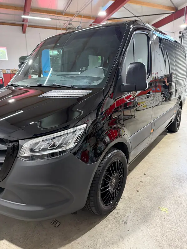Mercedes Sprinter nach der Lackaufbereitung, Frontpartie schräg von der Seite mit tiefem Schwarz – Siebers KFZ-Reinigung und Pflege