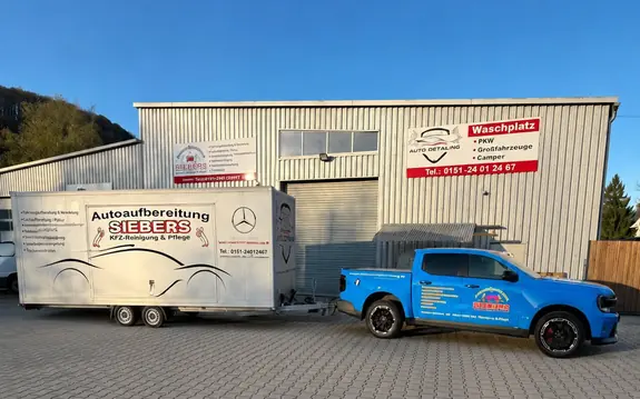 Betriebsgelände der KFZ-Aufbereitung Siebers an der Sauerlandstraße 123 in Marsberg-Bredelar mit Halle, Transportanhänger und Firmenfahrzeug