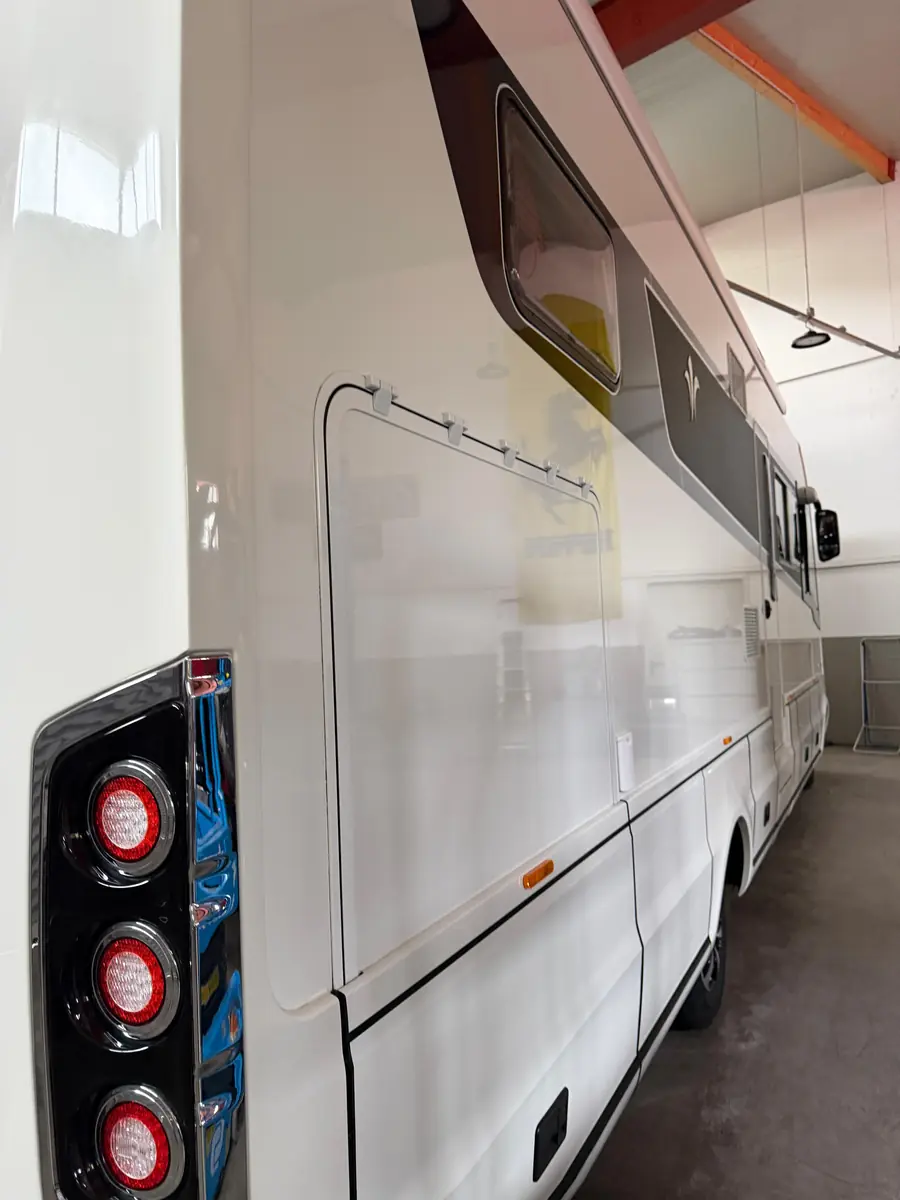 Flanke des Wohnmobils nach Politur und Versiegelung, Hallenfenster spiegeln sich im Lack – KFZ-Aufbereitung Siebers